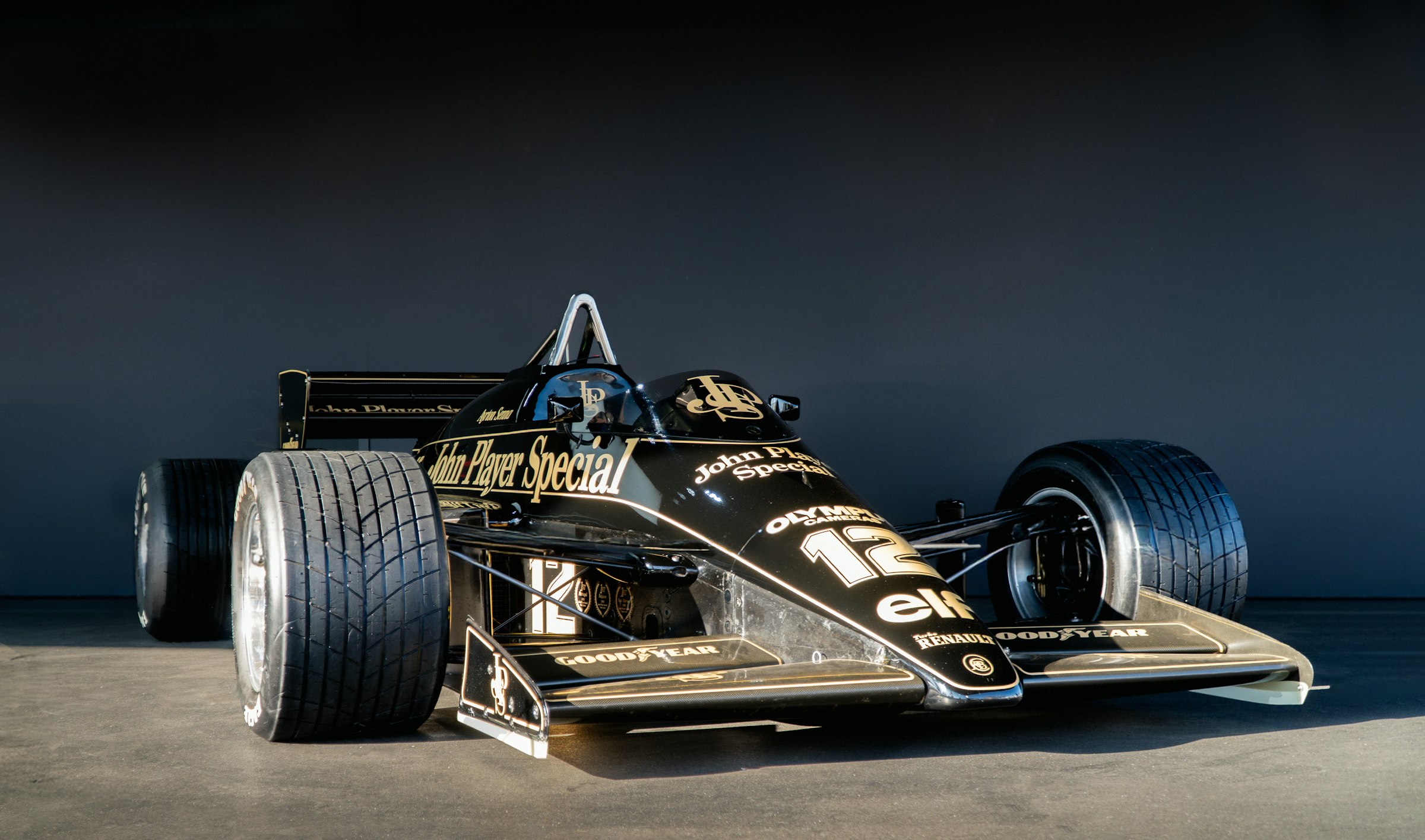 A black and gold 1980s Grand Prix car in studio light